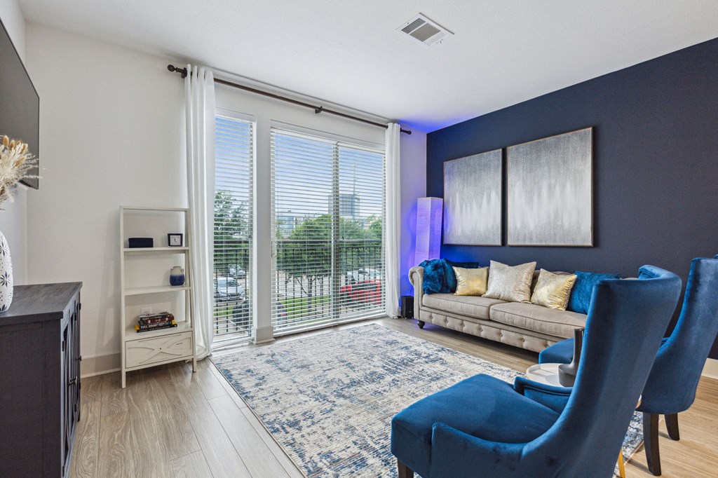 A living room with a blue chair and a couch at Everra Midtown Park Apartments, Texas