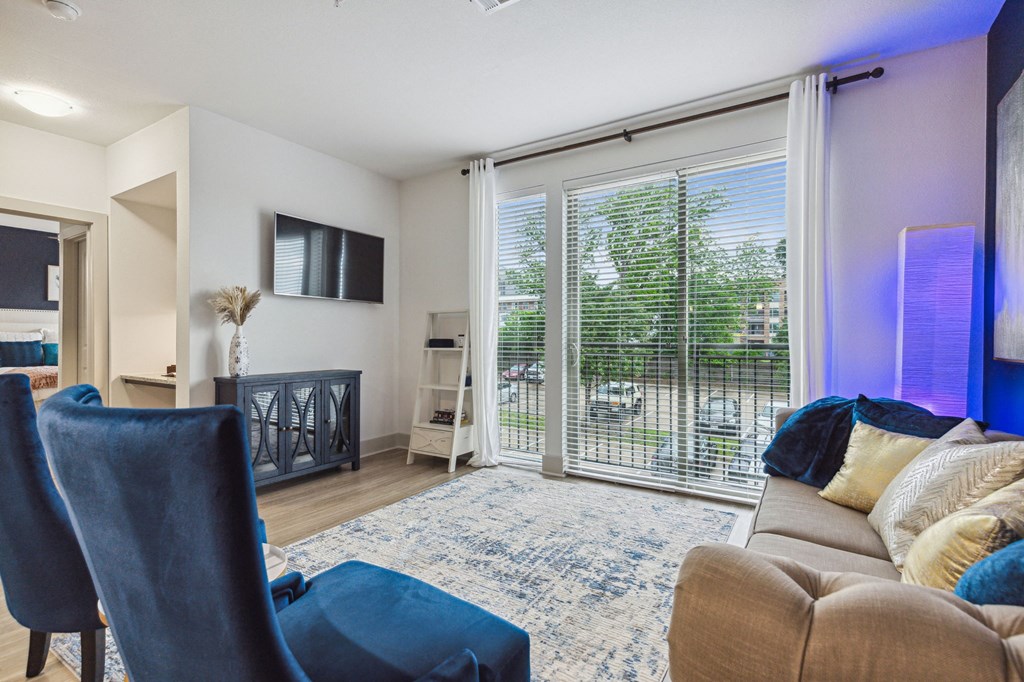 A living room with a blue chair and a brown couch at Everra Midtown Park Apartments, Texas, 75231