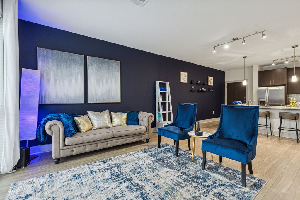 A living room with a grey couch, two blue chairs and a rug at Everra Midtown Park Apartments, Dallas, TX, 75231