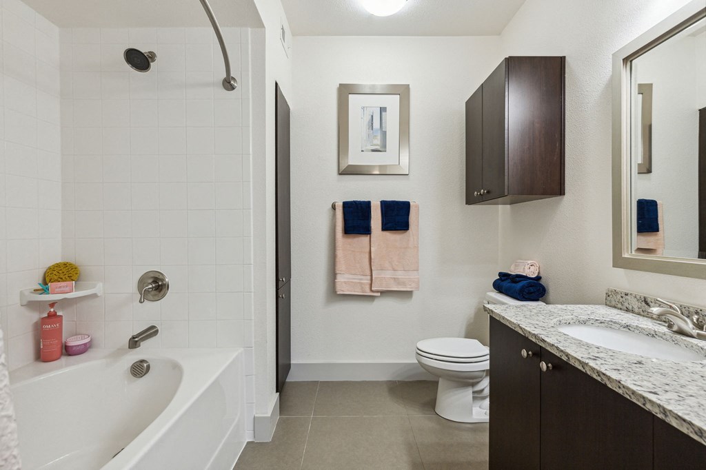 A bathroom with a white tub, toilet, and sink at Everra Midtown Park Apartments, Texas