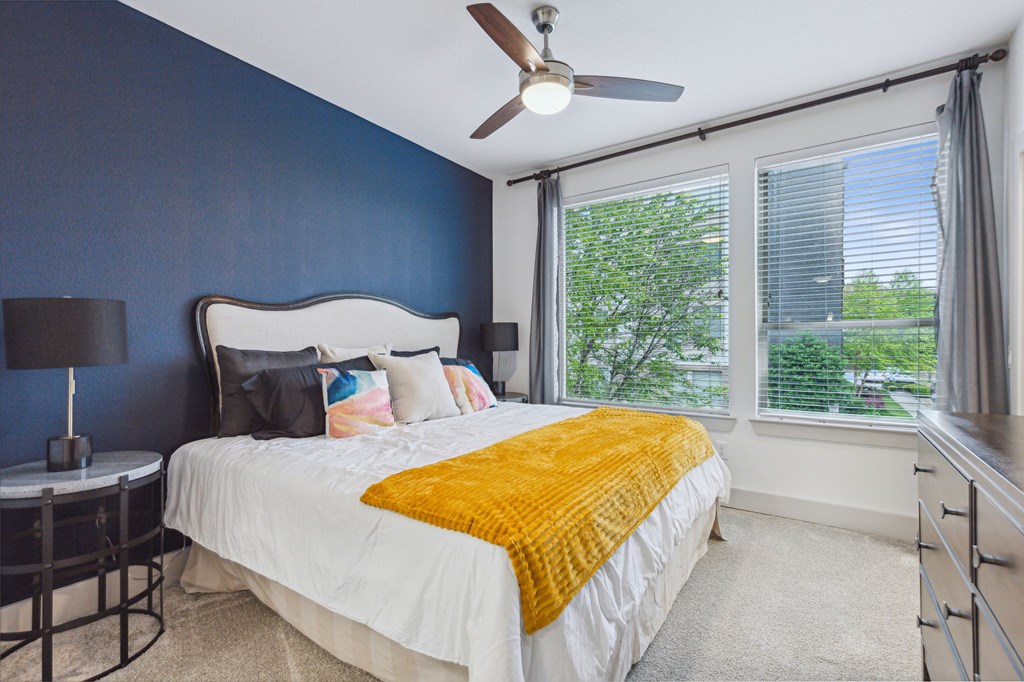 A bedroom with a white bed and a ceiling fan at Everra Midtown Park Apartments, Texas, 75231