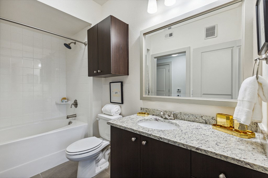 A white toilet sits next to a sink in a bathroom at Everra Midtown Park Apartments, Dallas, TX, 75231
