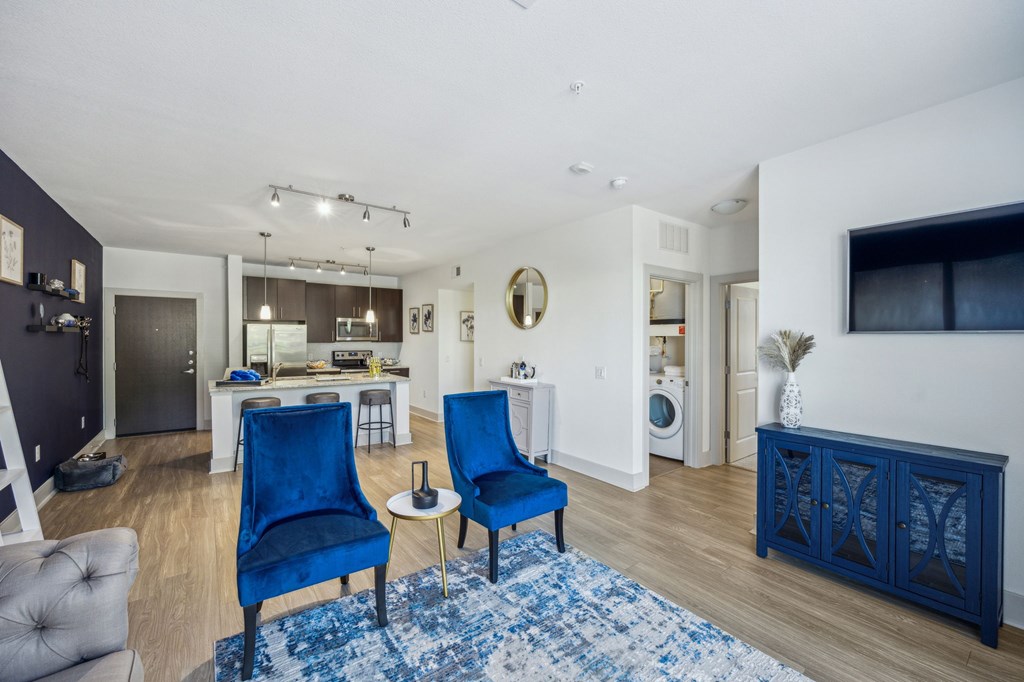 A living room with blue chairs and a white couch at Everra Midtown Park Apartments, Dallas, Texas