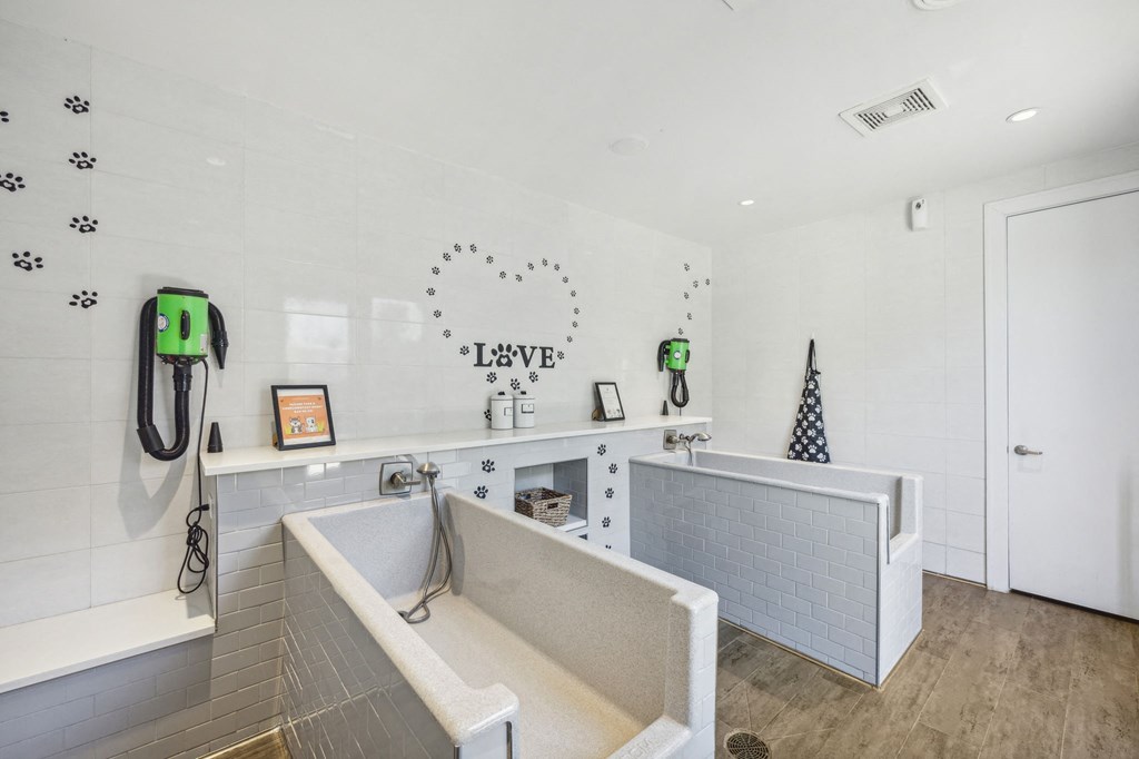 A bathroom with a white tub and a white door at Everra Midtown Park Apartments, Texas, 75231