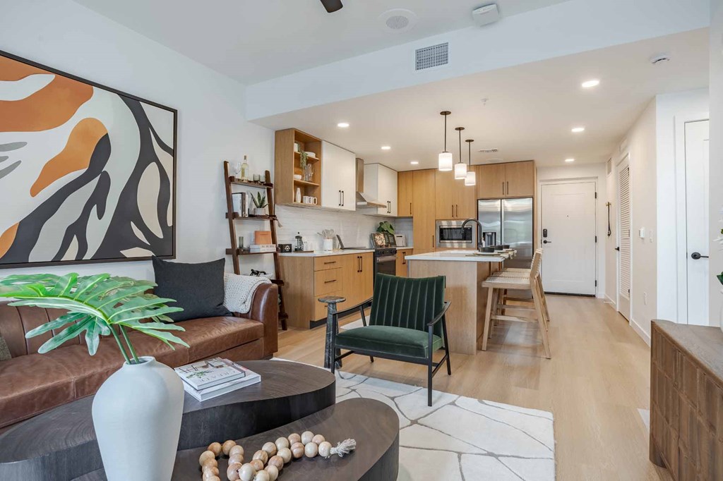 A modern kitchen with a brown couch and a green chair.