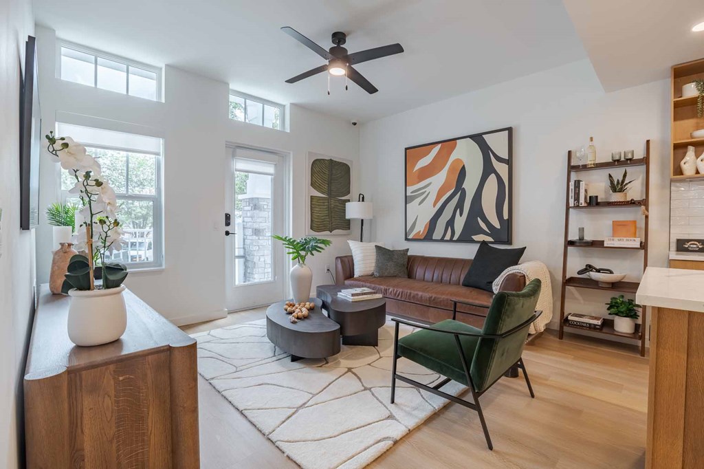A living room with a brown couch, a green chair, and a painting on the wall.