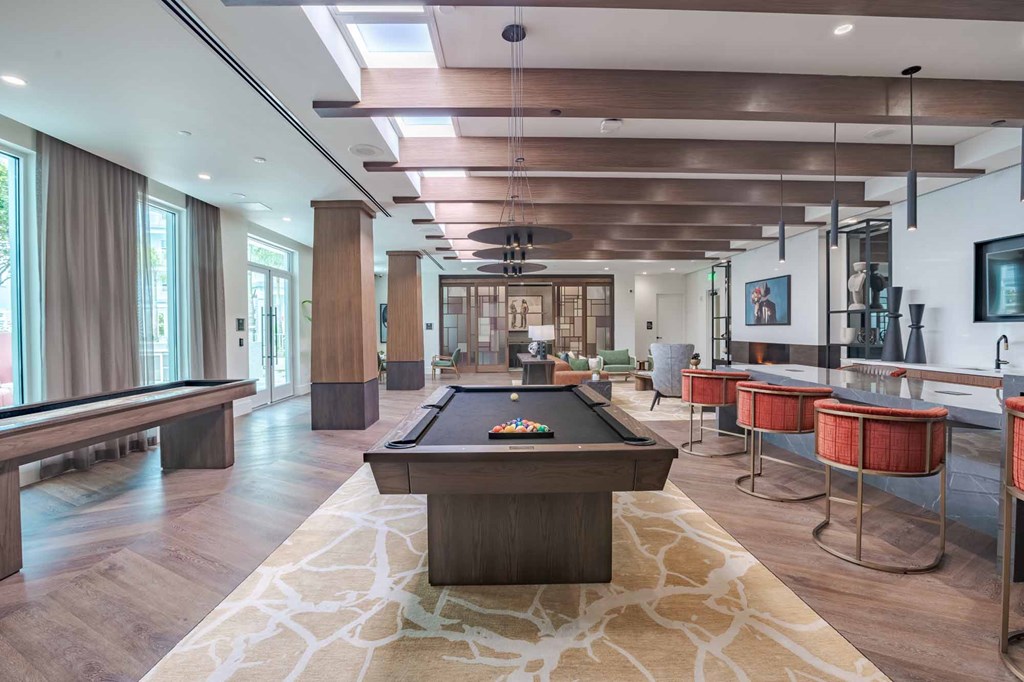 A billiard table is in the middle of a room with a pool table and a foosball table.