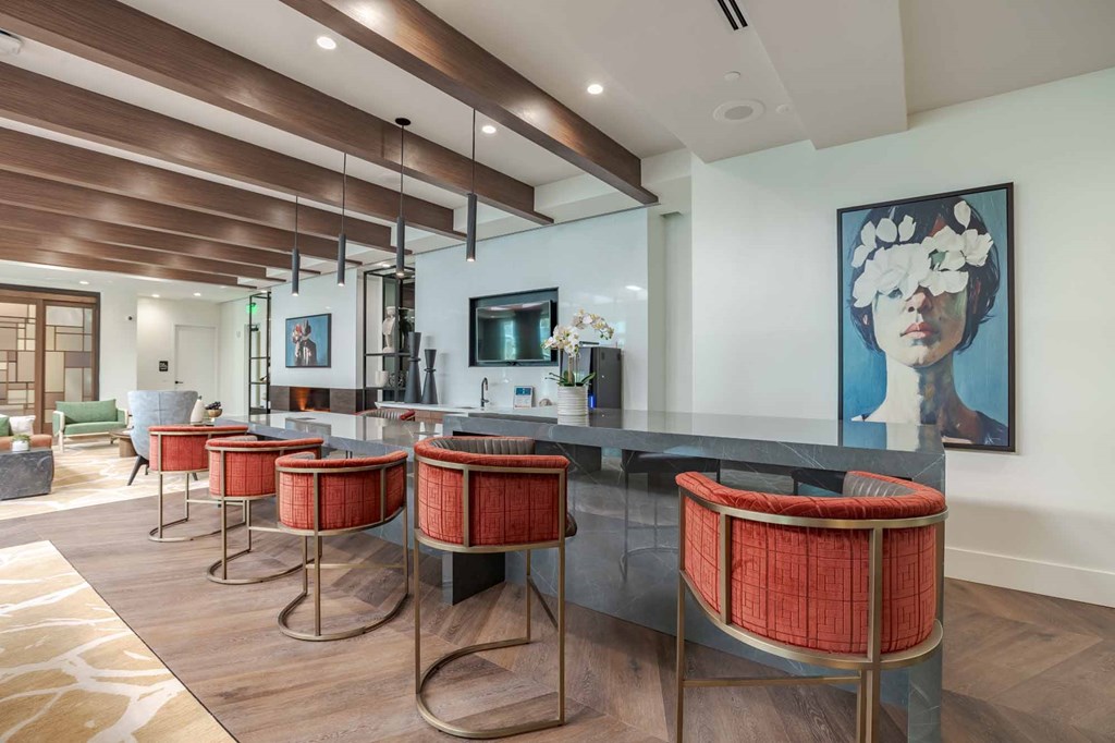 A modern kitchen with a bar area and a painting of a woman's face on the wall.