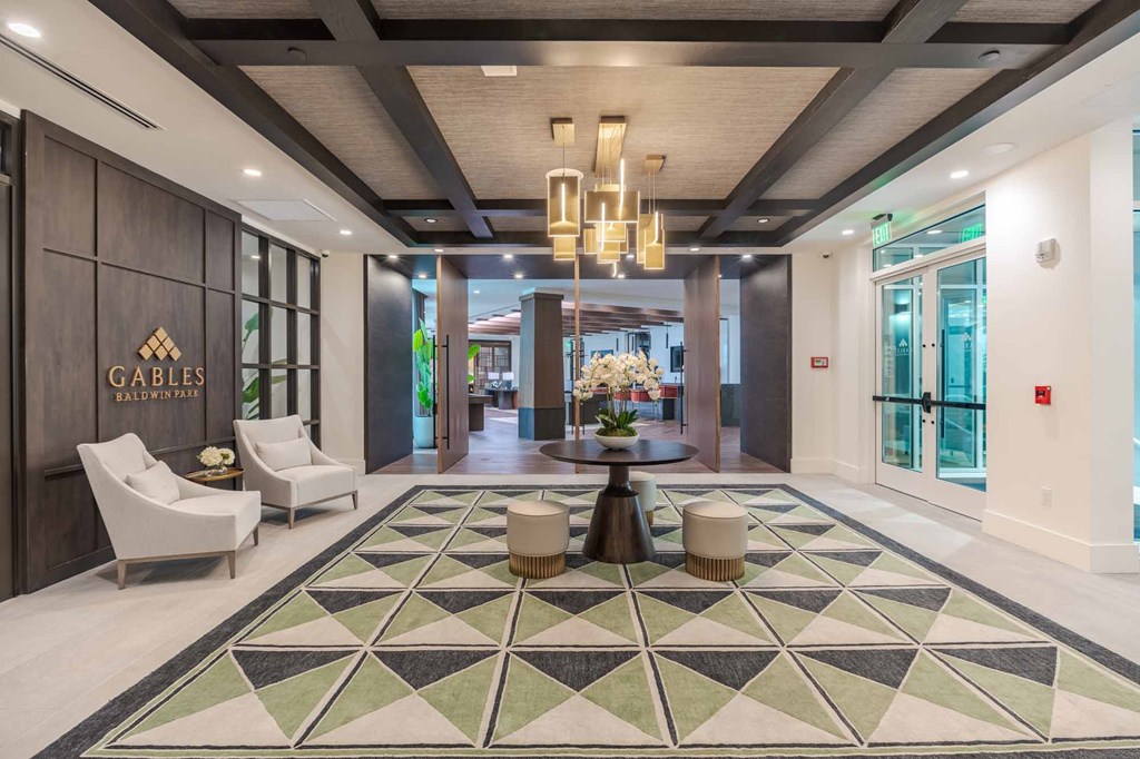 A lobby with a large rug and chairs.