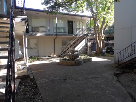 A courtyard with a fountain and a tree.