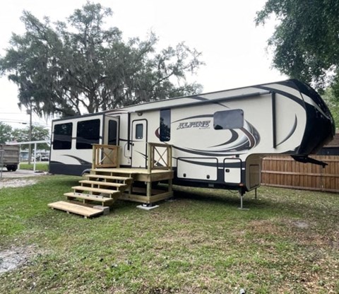 A white and black RV is parked in a grassy area.