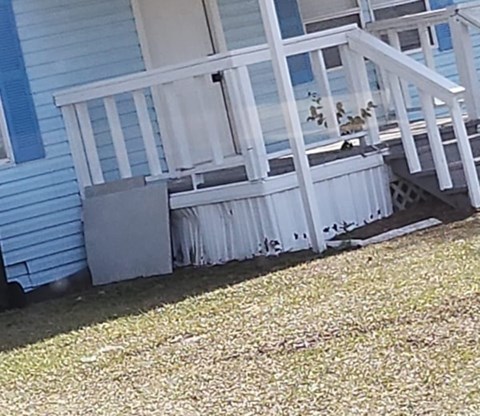 A blue house with a white porch and a white railing.