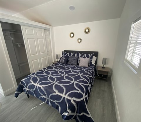 A bedroom with a bed, nightstand, and a wall clock.