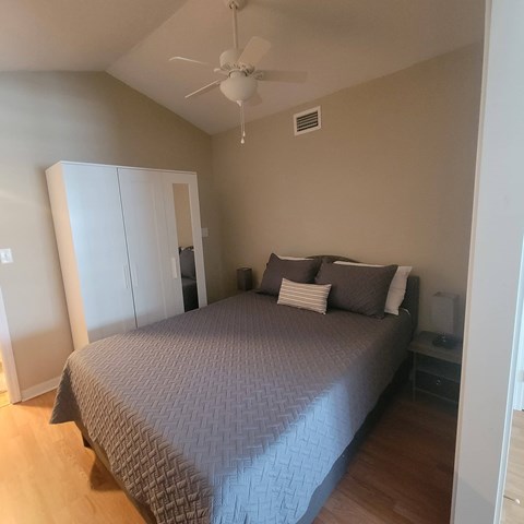 A bedroom with a bed, pillows, and a ceiling fan.