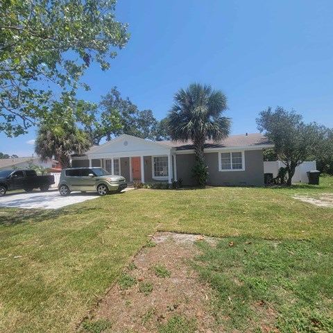 A house with a green lawn and a tree in front.
