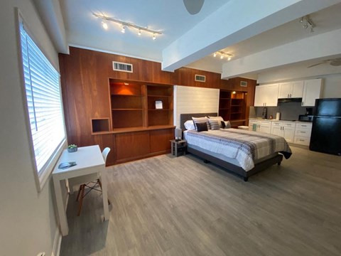 A bedroom with a bed, desk, and a television.