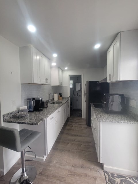 A kitchen with white cabinets and a granite countertop.
