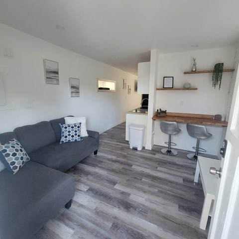A living room with a grey couch and a bar area.
