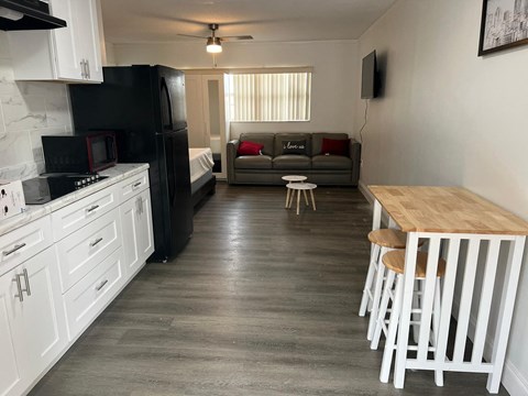 A kitchen with a black refrigerator and white cabinets.