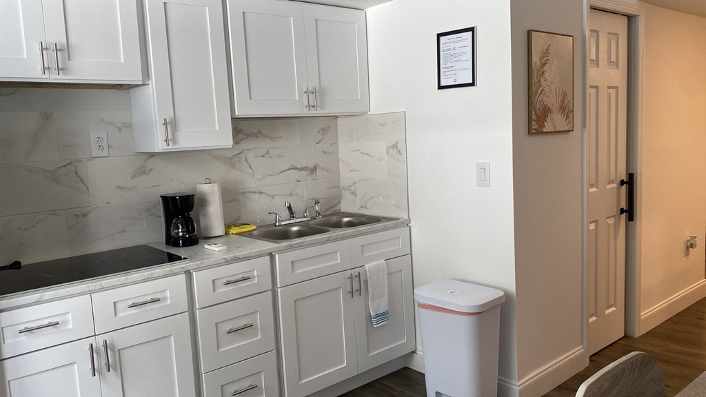 A kitchen with white cabinets and a marble countertop.