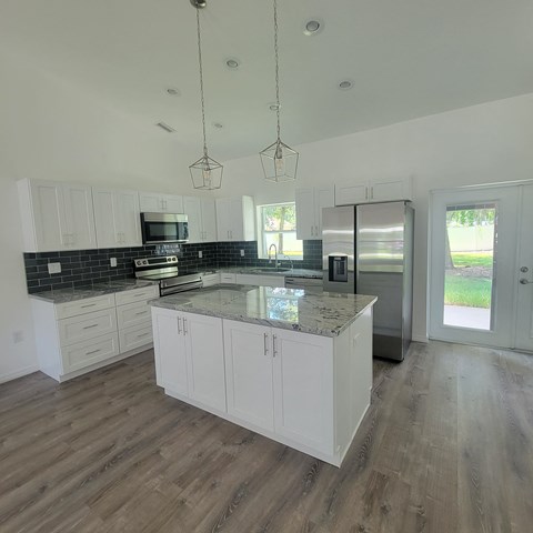 A kitchen with white cabinets and a black backsplash.