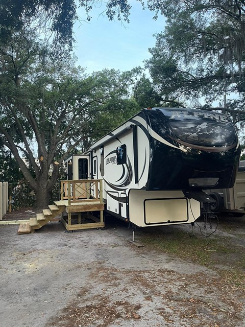 A black and white RV is parked in a wooded area.