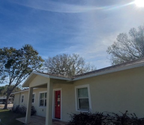A house with a red door and white trim under a blue sky.