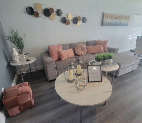 A living room with a grey couch, a white coffee table, and a wall art.