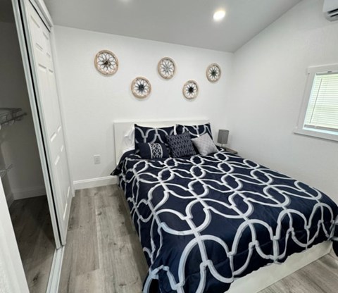 A bed with a white and navy blue comforter is in a room with a window and three circular wall decorations.
