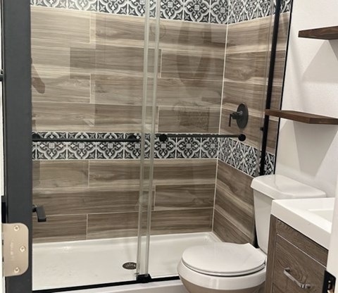 A bathroom with a toilet, sink, and tiled shower.