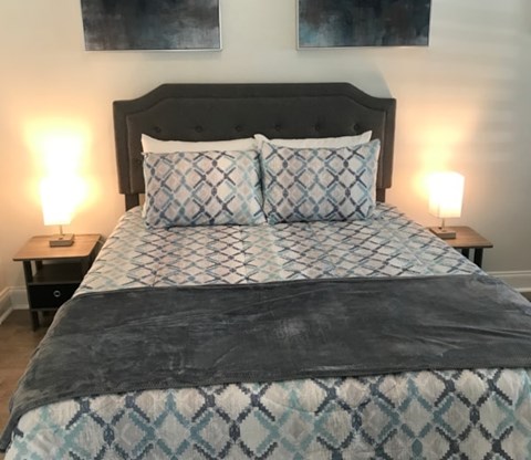 A bed with a black headboard and a blue and white patterned comforter.