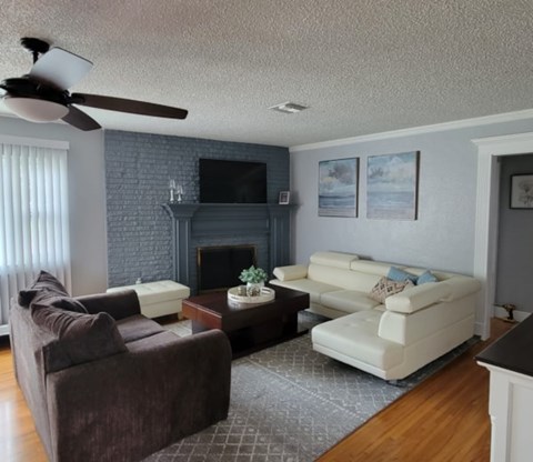 A living room with a brown couch, a white couch, and a fireplace.