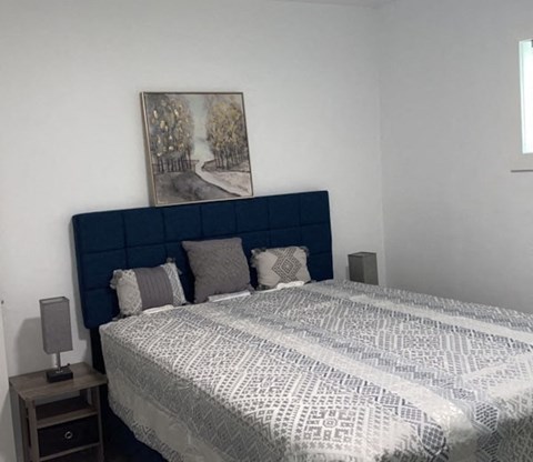 A bed with a blue headboard and a grey and white patterned duvet cover.