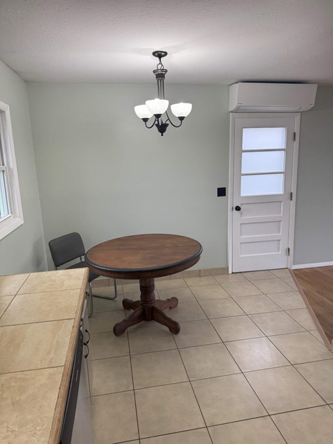 A dining room with a round wooden table and a chandelier.