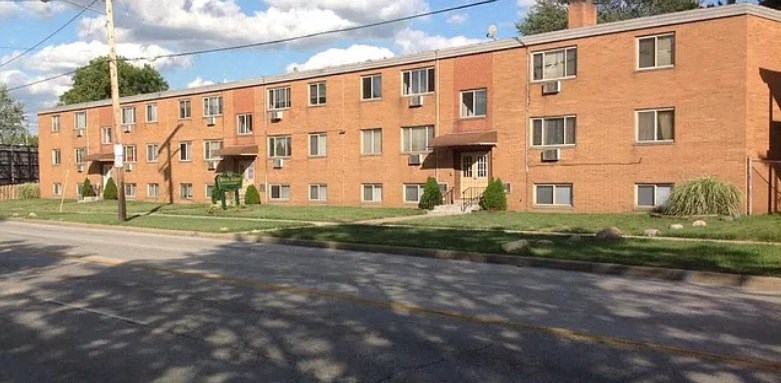A red brick apartment building with a green lawn in front.