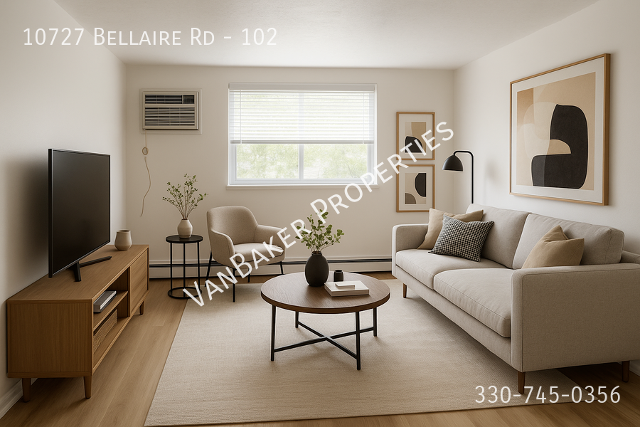 A living room with a sofa, a coffee table, a television, and a plant.