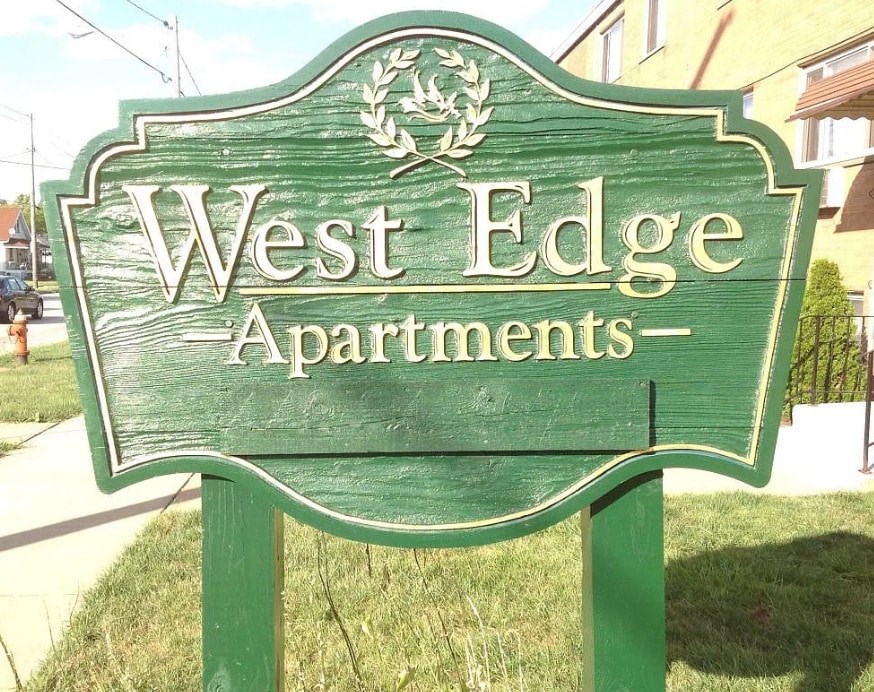 A green sign that says West Edge Apartments.