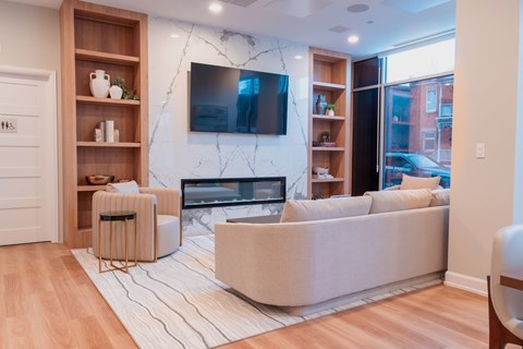 A living room with a white couch and a television mounted on the wall.