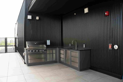A black outdoor kitchen with a grill and sink.