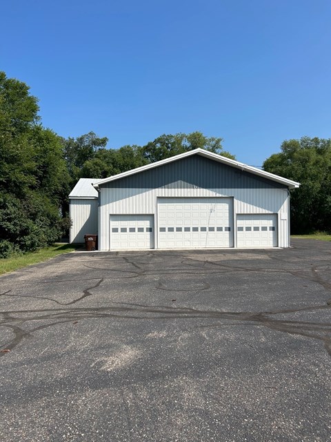 A large metal building with a garage door is situated in a parking lot.