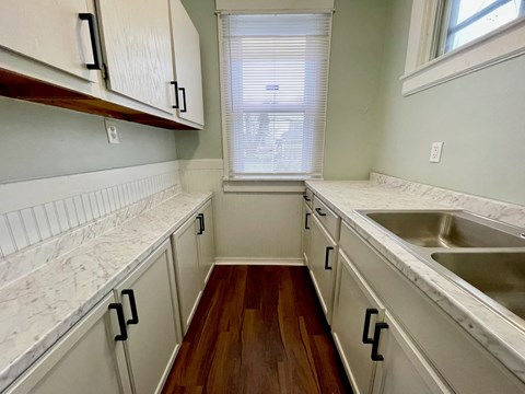 A kitchen with white cabinets and a marble counter top.