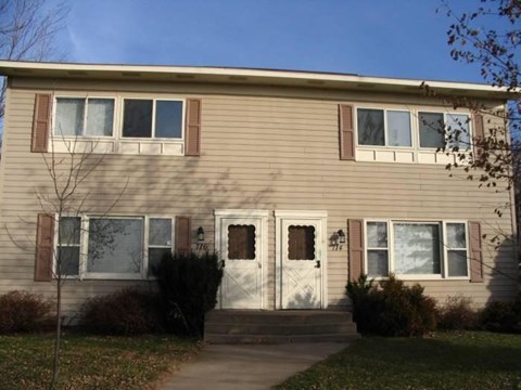 A beige house with a white door and windows.