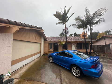 A blue car is parked in front of a house.