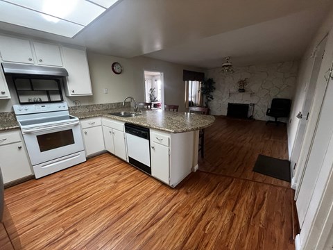 A kitchen with white cabinets and a wooden floor.