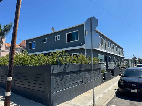 A grey house with a black car parked in front.