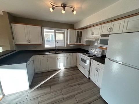 A kitchen with white cabinets and a black countertop.