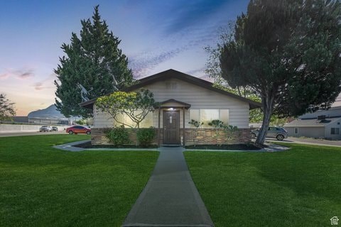 A house with a brown roof and a brown door is surrounded by a green lawn.