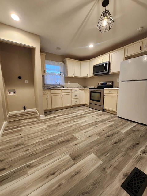 A kitchen with wooden floors and white appliances.