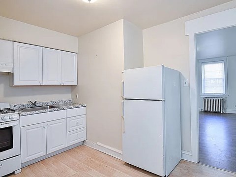 A white kitchen with a refrigerator and a stove.