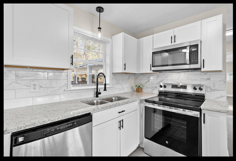 A kitchen with white cabinets and a black dishwasher.